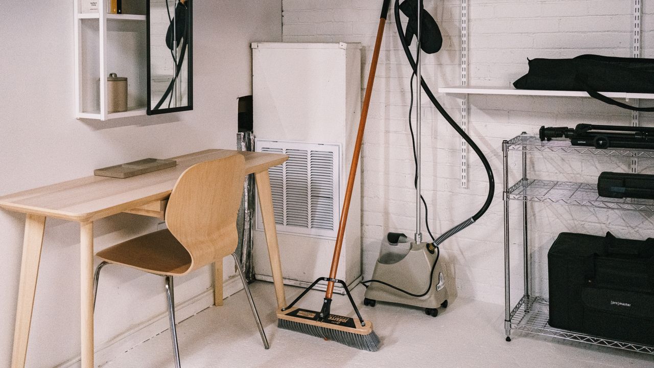 about-01 A tidy home office space featuring a wooden desk, chair, broom, and cleaning equipment.